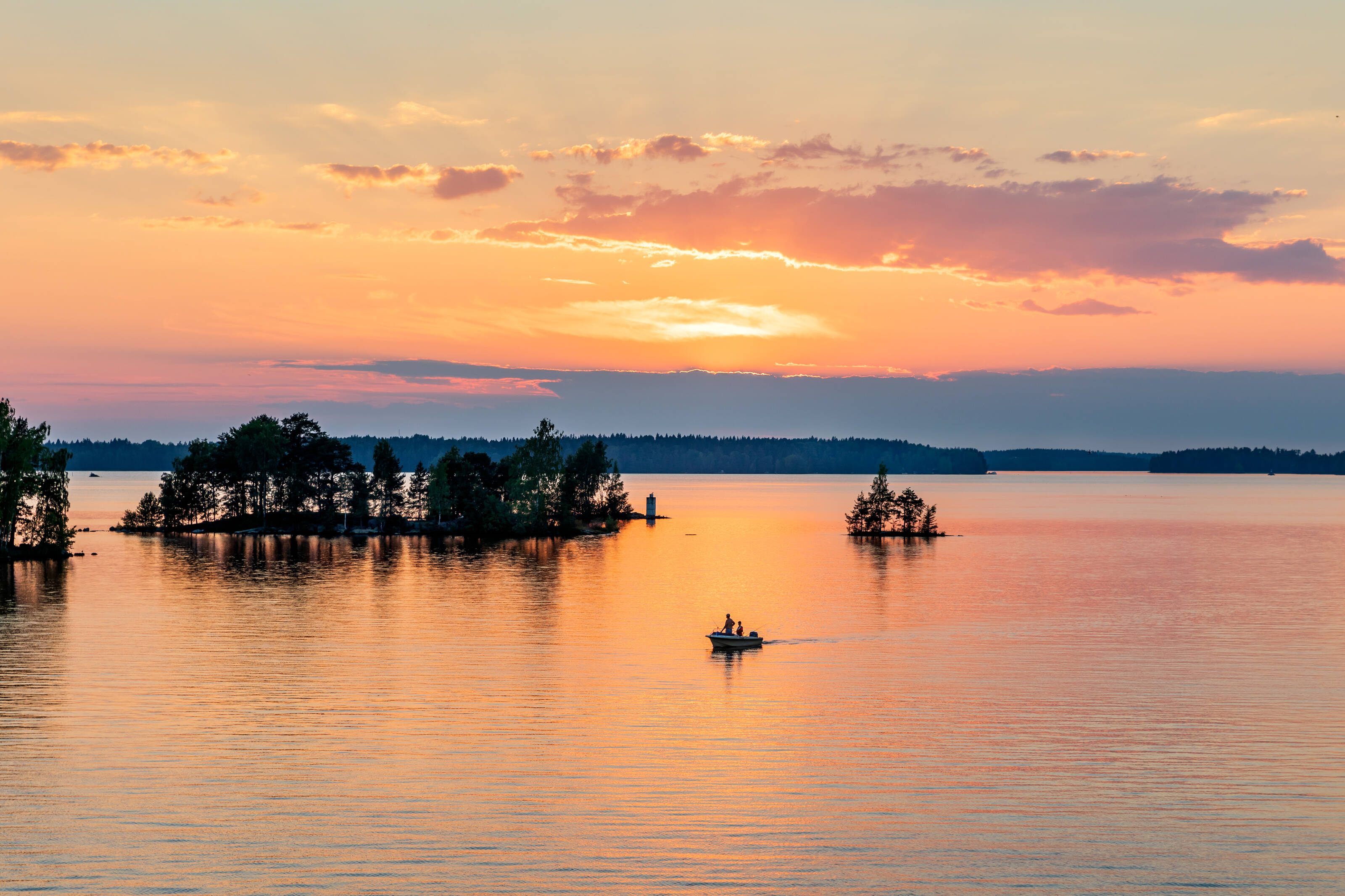 People in the Turku archipelago in a boat under the midnight sun.